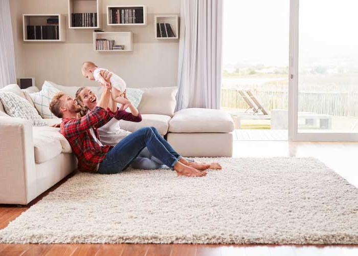 Young white couple play with their toddler in sitting room